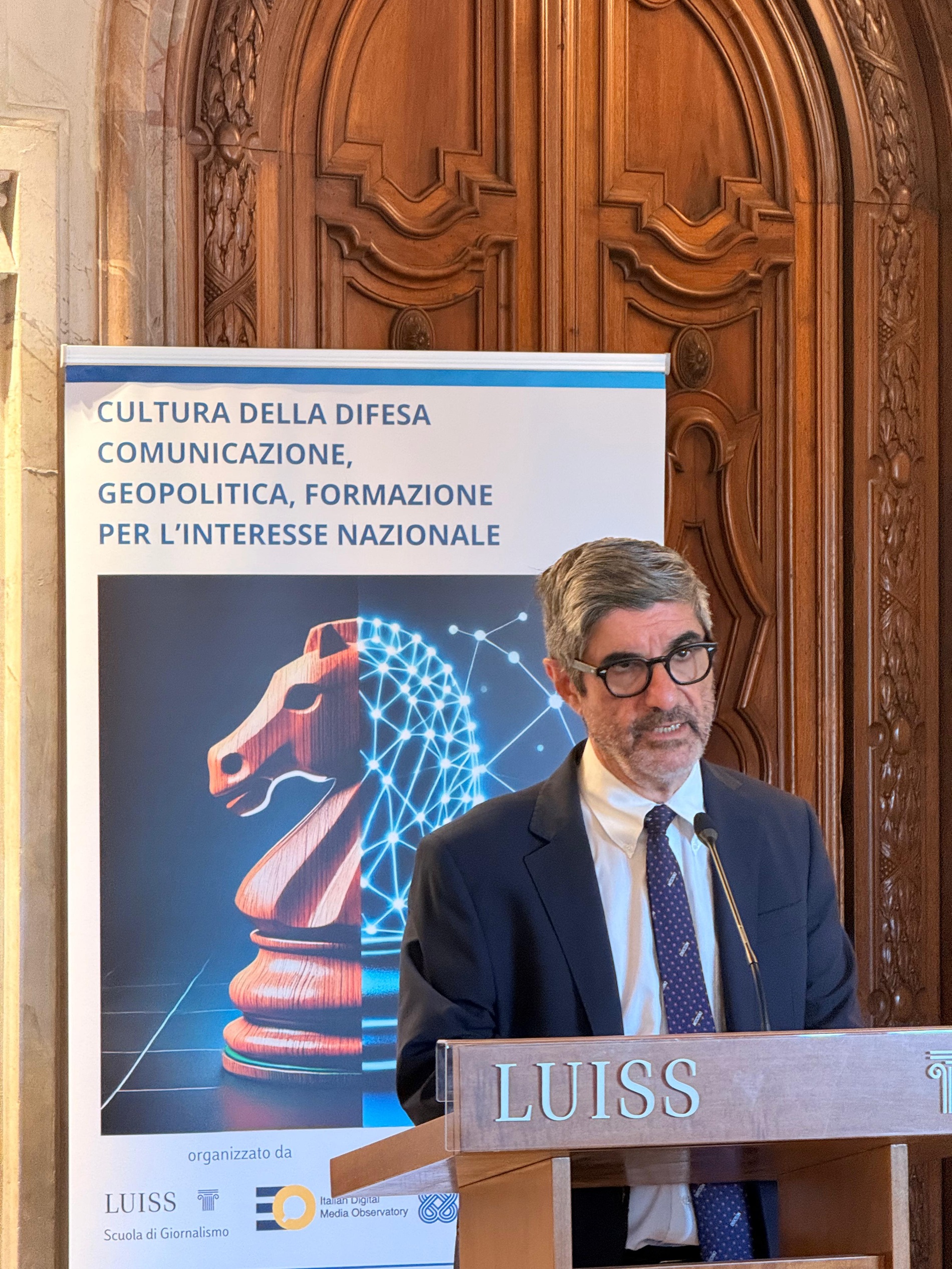 Relatore al podio con locandina sullo sfondo